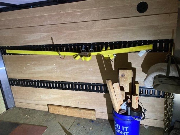 Tie-down straps clipped into E-Track inside the enclosed cargo trailer